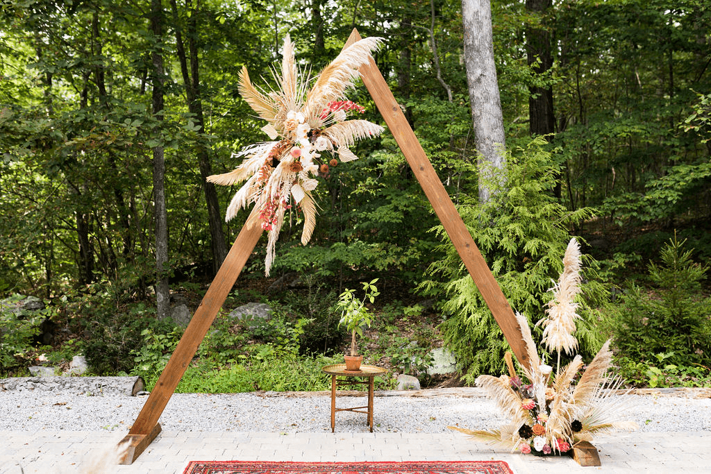 A close up of the wedding alters with a wooden arch and flowers