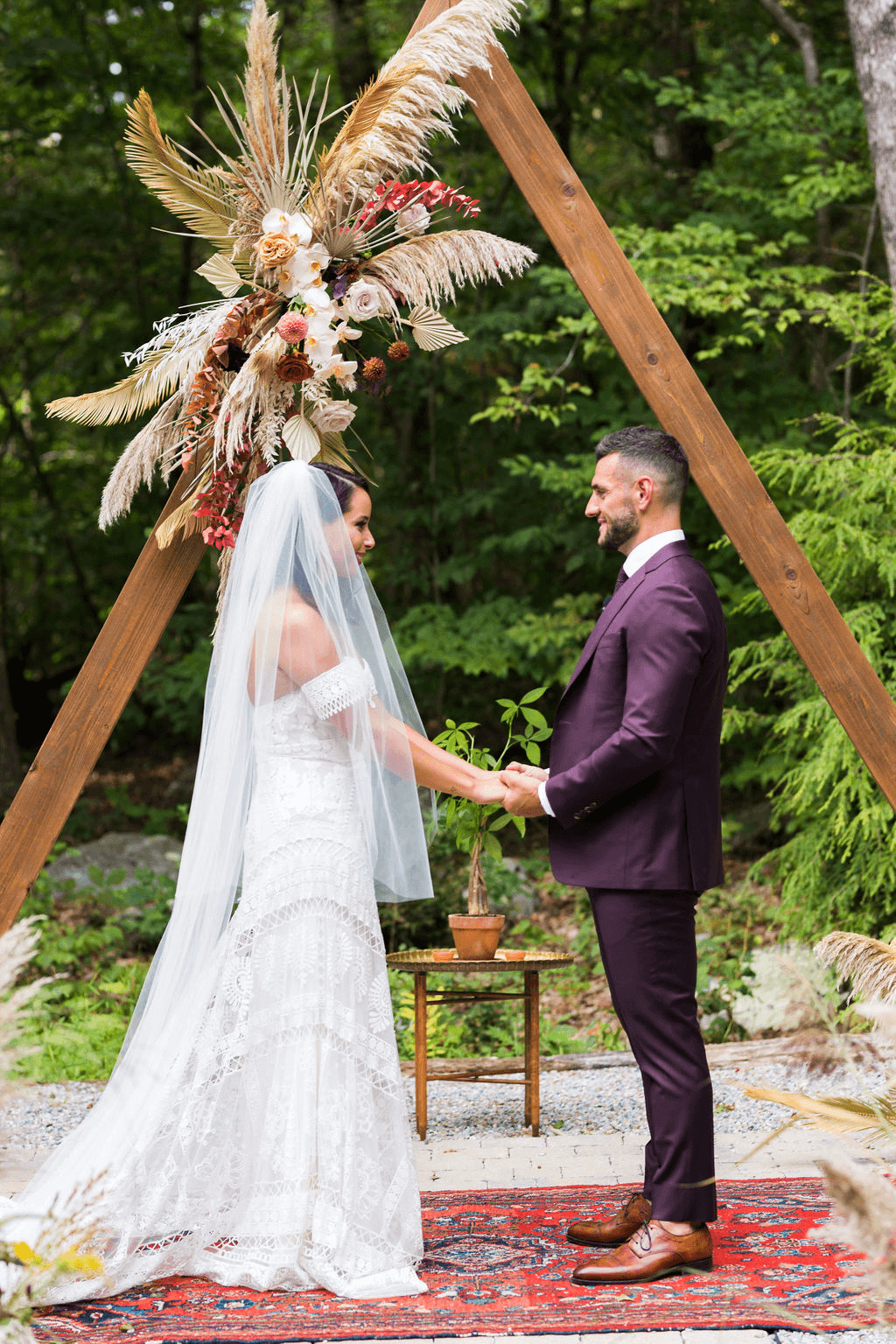 Bride and groom hold hands while facing each other at the altar