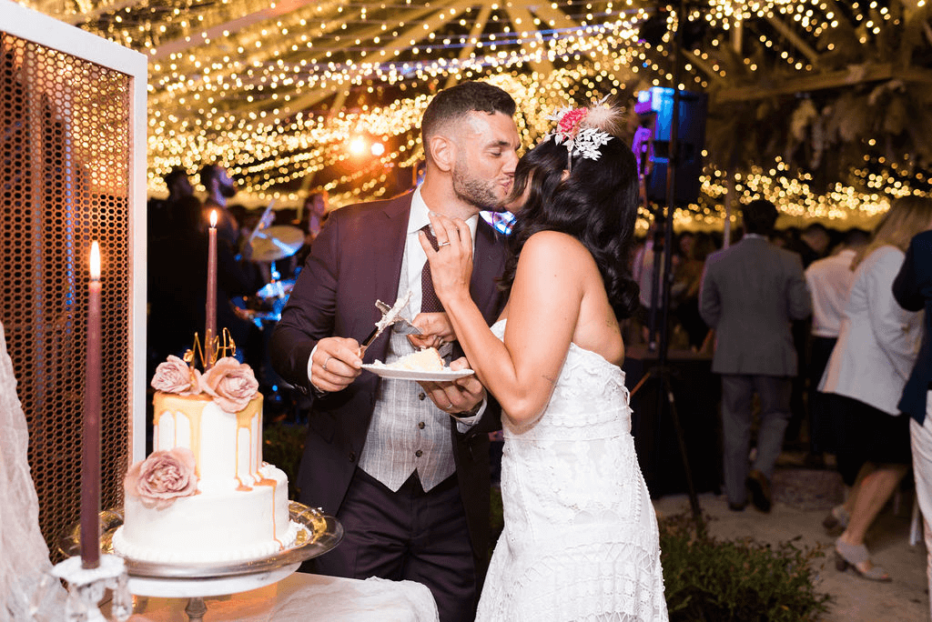 Bride and groom kiss after cutting their wedding cake