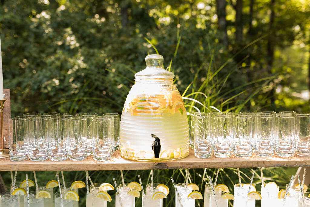 Glasses filled with lemonade surround a lemonade dispenser