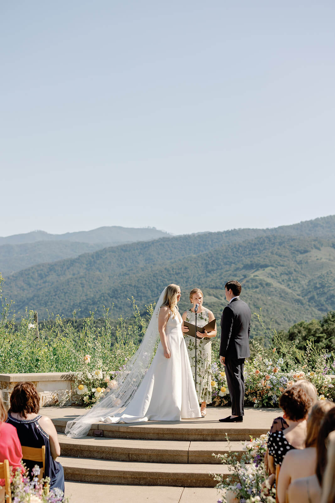 Bride and groom at the alter overlooking vineyards and mountains of California during their destination wedding.